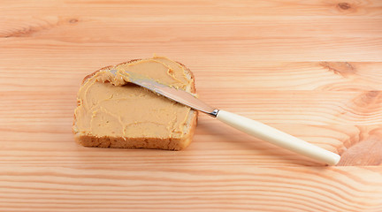 Image showing Spreading peanut butter onto a slice of bread