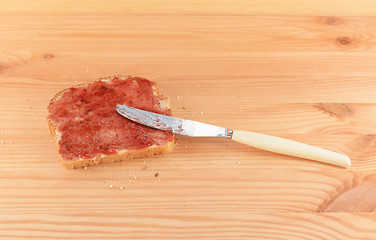 Image showing Spreading jam on fresh bread with a knife