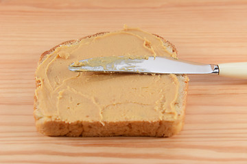 Image showing Smooth peanut butter being spread onto bread