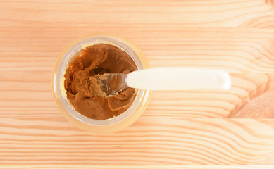 Image showing Knife rests in a jar of smooth peanut butter