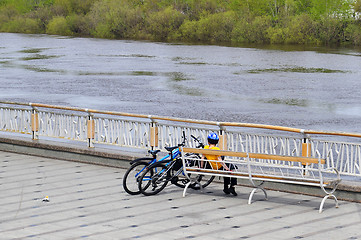 Image showing The boy with two bicycles sits on a shop on the embankment in Ty