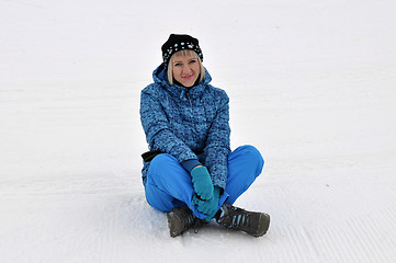 Image showing The woman in winter clothes sits on snow.