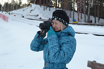 Image showing The woman in winter clothes photographs the SLR camera.