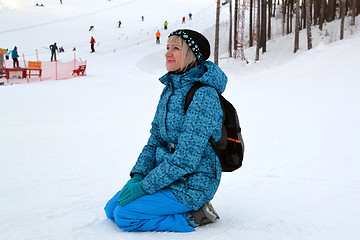 Image showing The woman in winter clothes sits on snow against the ski slope.