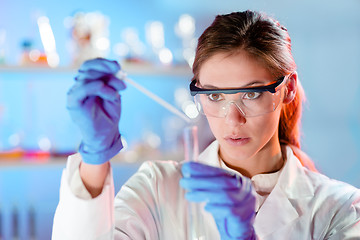 Image showing Attractive young scientist pipetting.