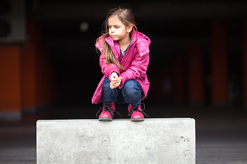 Image showing A sad little girl crouching down