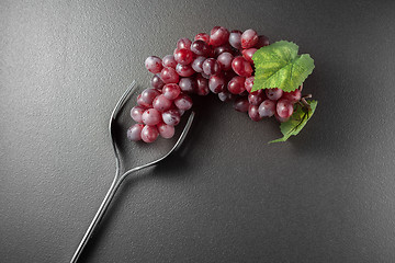 Image showing Wine glass made of forks and grape on black