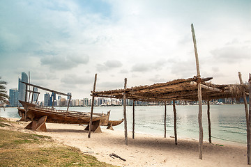 Image showing sea beach with old wooden boath and luxury skyscarper