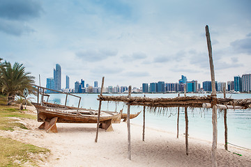 Image showing sea beach with old wooden boath and luxury skyscarper