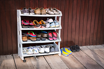 Image showing Colorful Shoes on a Plastic Shoe Rack, Outside a House