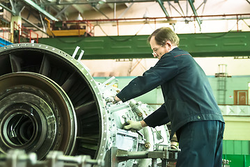 Image showing Elderly mechanic assembles aviation engine