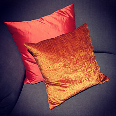 Image showing Shiny red and orange cushions decorating a sofa