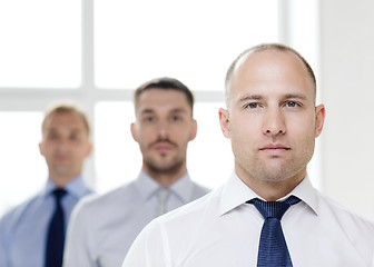 Image showing serious businessman in office with team on back