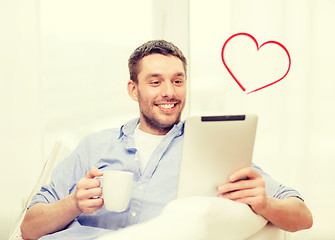 Image showing smiling man working with tablet pc at home