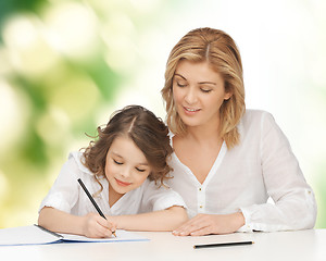 Image showing happy mother and daughter writing in notebook