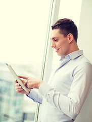 Image showing smiling businessman with tablet pc in office