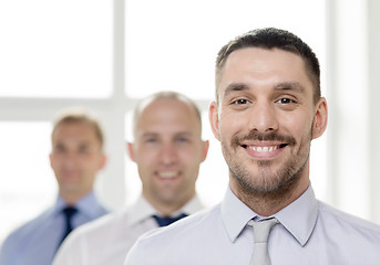 Image showing smiling businessman in office with team on back