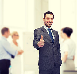 Image showing handsome buisnessman showing thumbs up in office