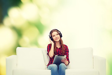 Image showing girl sitting on sofa with headphones and tablet pc