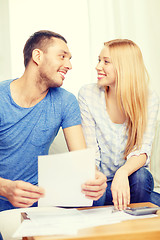 Image showing smiling couple with papers and calculator at home