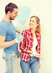 Image showing smiling couple painting small heart on wall