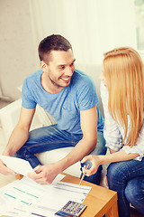 Image showing smiling couple with papers and calculator at home