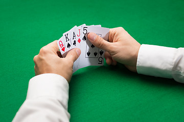 Image showing poker player holding playing cards at casino table