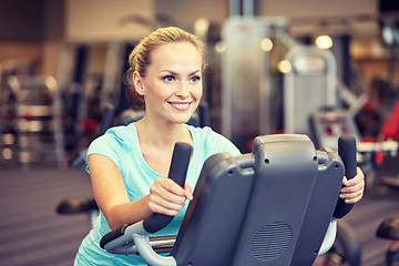 Image showing smiling woman exercising on exercise bike in gym