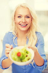 Image showing smiling young woman with green salad at home