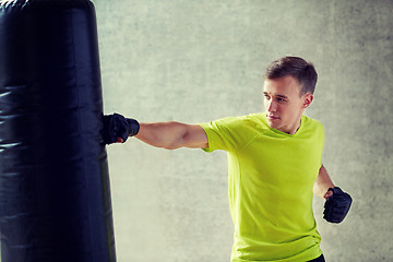 Image showing young man in gloves boxing with punching bag