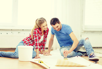 Image showing smiling couple smearing wallpaper with glue