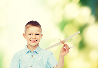 Image showing smiling little boy holding a wooden airplane model