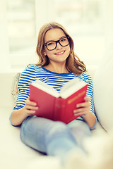 Image showing smiling teenage girl reading book on couch