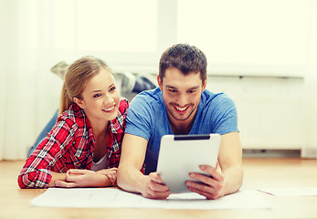 Image showing smiling couple looking at tablet pc at home