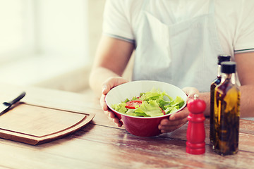 Image showing close of male hand holding a bowl with salad