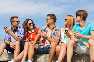 Image showing group of smiling friends with smartphones outdoors