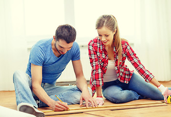 Image showing smiling couple measuring wood flooring