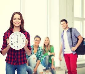 Image showing young woman in casual clothes with wall clock