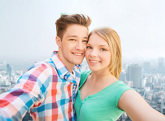 Image showing smiling couple with smartphone in city background