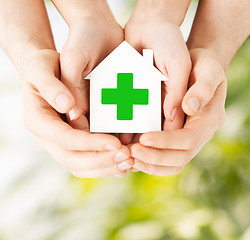 Image showing hands holding paper house with green cross