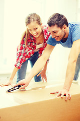 Image showing smiling couple opening big cardboard box