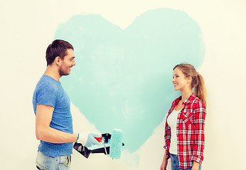 Image showing smiling couple painting big heart on wall