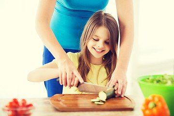 Image showing smiling little girl with mother chopping cucumber