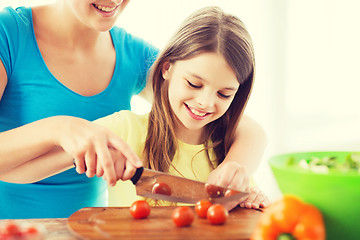 Image showing smiling little girl with mother chopping tomatoes