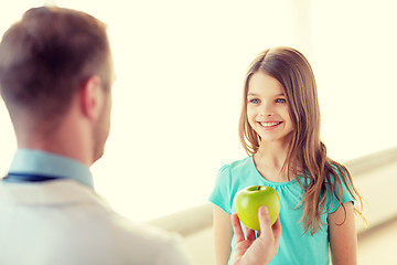 Image showing male doctor giving an apple to smiling little girl