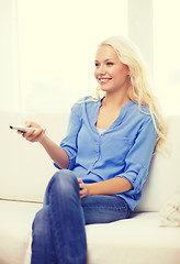 Image showing smiling young girl with tv remote control at home