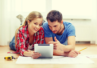 Image showing smiling couple looking at tablet pc at home