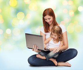 Image showing happy mother with adorable little girl and laptop