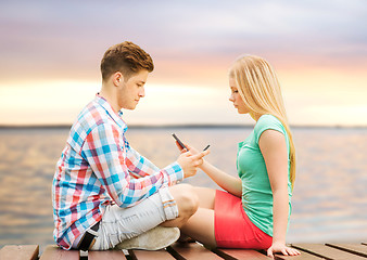 Image showing couple with smartphones sitting on bench