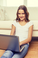 Image showing smiling teenage girl with laptop computer at home